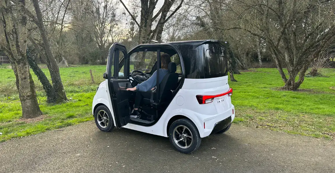 De IMF Industries E-Confort staat geparkeerd op de parkeerplaats bij een park, met de deuren open.